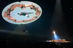 West lies on the stage with main dancers as the LED screen hangs above.